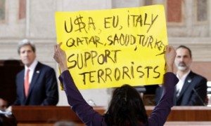 A peace activist who would not give her name protests what she said is the killing of innocent civilians by countries including the U.S. and Italy, at the end of statements given by U.S. Secretary of State John Kerry, pictured at left, and Syrian National Coalition President Mouaz al-Khatib, right, at Villa Madama in Rome, Italy, on Thursday, Feb. 28, 2013. (AP Photo/Riccardo De Luca)