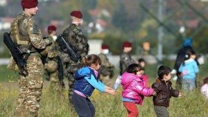 des-enfants-jouent-pres-de-soldats-slovenes-devant-la-file-de-migrants-et-refugies-venant-de-passer-la-frontiere-le-26-octobre-2015_5452716