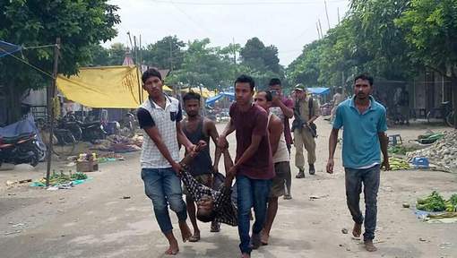 TOPSHOT - Villagers carry an injured person from the site of a militant attack at Balajan Tinali, in the Kokrajhar district of northeastern Assam state on August 5, 2016. Gunmen opened fire on a busy market in a restive area of northeast India, killing 12 people and wounding several others, police said. / AFP PHOTO / STR