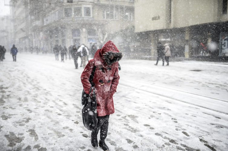 A woman walks under the snow in Istanbul on January 7, 2015. Heavy snowfall descended on large parts of Turkey snarling road and air traffic and leading to closures of schools, reports said. AFP PHOTO / BULENT KILIC